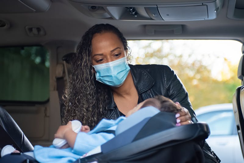 A parent securing an infant in a car seat